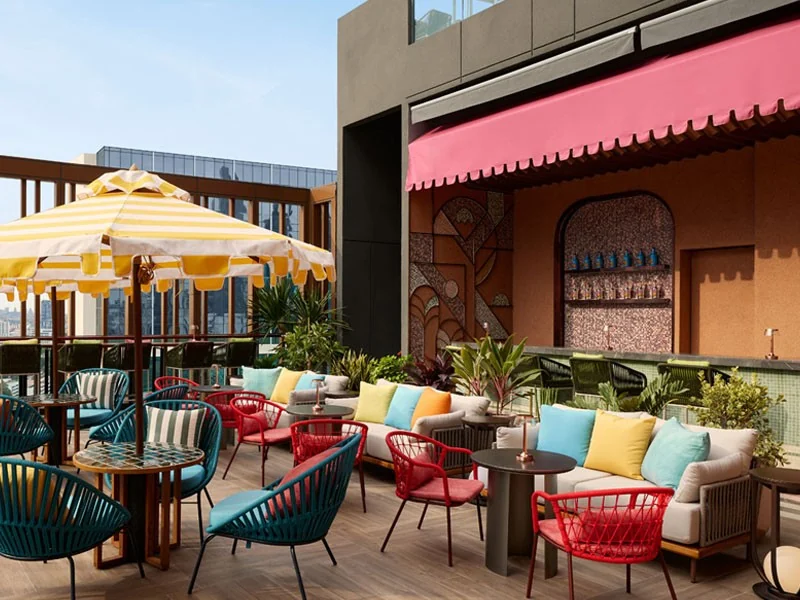 Mimi’s rooftop terrace by day with striped parasols, colourful cushions and wicker chairs